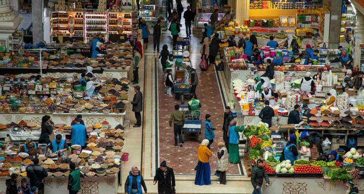 Halle de marché intérieure animée avec de nombreux étals vendant des fruits secs, des épices et des produits frais, vue d'en haut.