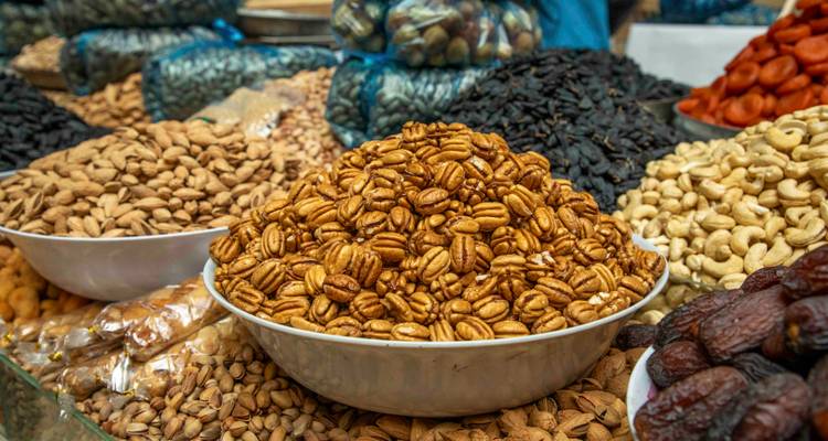 Bols empilés hauts avec des noix assorties et des fruits secs sur un étal de marché.