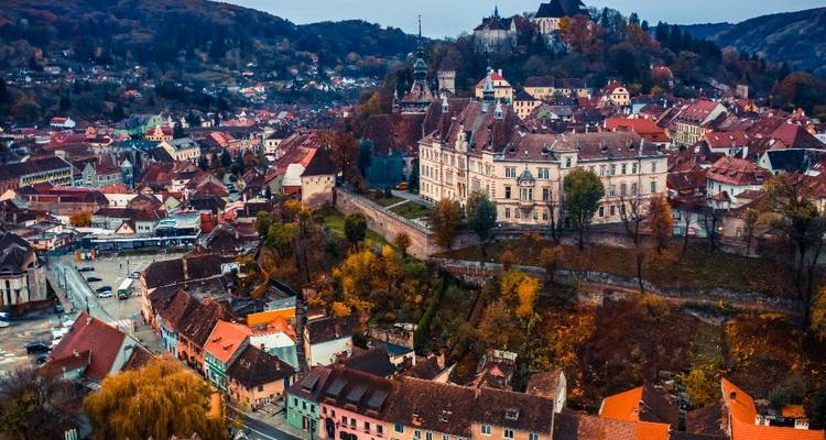 Verhoogd herfstbeeld van Sighișoara met kleurrijke daken, middeleeuwse vesting en omliggende heuvels