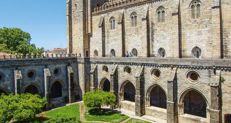 Claustros de piedra medievales y jardín dentro de un complejo catedralicio histórico.