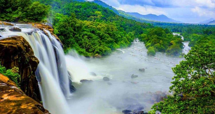 Levendige waterval die in nevelige tropische riviervallei stort, omringd door dicht regenwoud.