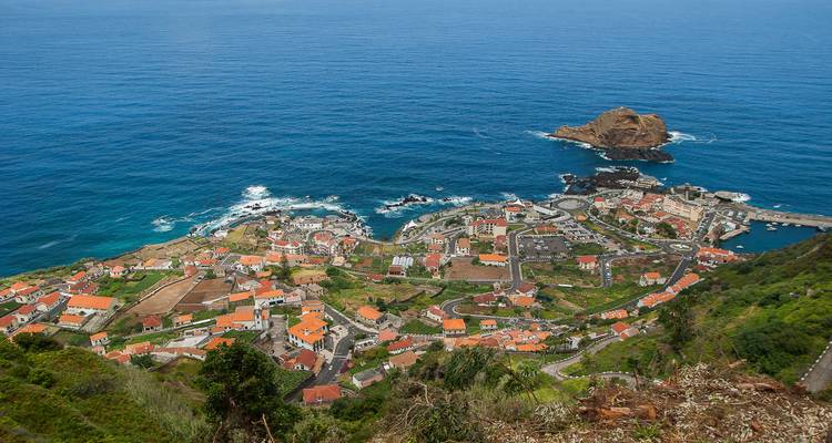 Una vista elevada muestra el pueblo costero de Porto Moniz y sus piscinas naturales a lo largo de la costa escarpada.