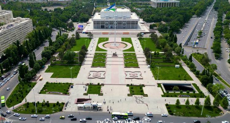 Vue à vol d'oiseau d'une grande place et de jardins formels menant à un bâtiment gouvernemental blanc à Tachkent.