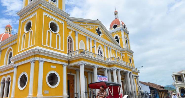 Cathédrale néo-classique jaune vif avec des dômes rouges sous un ciel partiellement nuageux à Grenade.