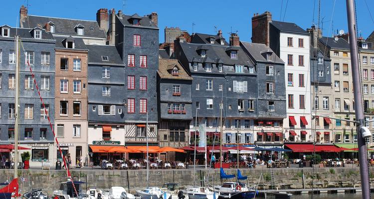 Bunte schieferverkleidete Häuser und Café-Terrassen säumen Honfleurs alten Hafen mit Masten vertäuter Yachten
