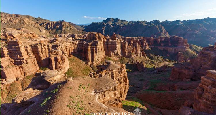 Vue panoramique sur des formations de canyon rouge accidenté au coucher du soleil avec filigrane de visite.