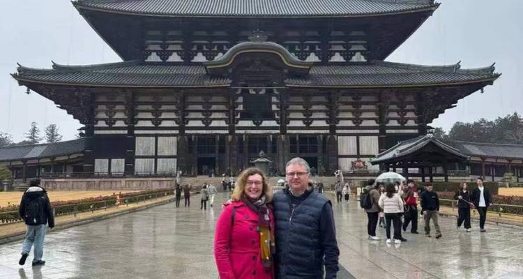 Couple poses before massive wooden Todai-ji temple on rainy day.