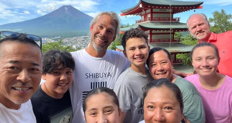 Smiling multi-generational group selfie in front of the Chureito Pagoda with snow-capped Mount Fuji towering in the background.