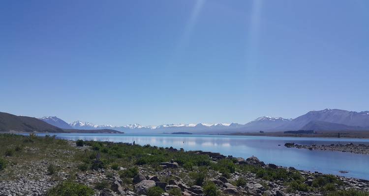 Lac cristallin reflétant les Alpes du Sud enneigées sous un ciel bleu éclatant