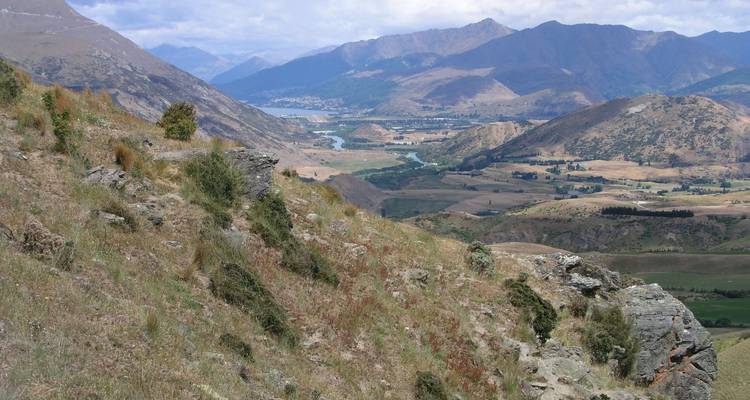 Paysage vallonné accidenté surplombant une vallée et un lac lointain en Nouvelle-Zélande