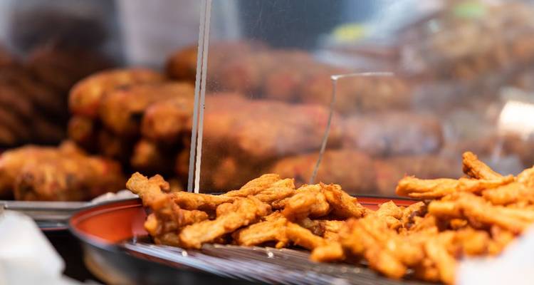 Close-up van gouden gebakken straatvoedstukjes op een dienblad bij een kraam.