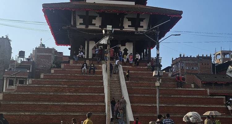 Mehrstöckiger Pagoden-Tempel mit Menschen, die die zentrale Treppe hinaufsteigen und sich auf den Plattformen versammeln.