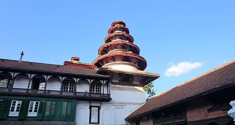 Markanter roter gestufter Turm, der sich über traditionelle Gebäude gegen einen klaren blauen Himmel erhebt.