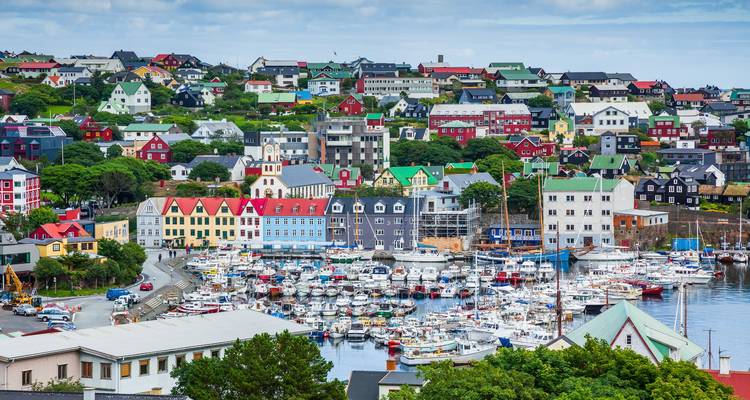 Panoramablick auf Tórshavns bunte Hangvillen und den lebhaften Yachthafen voller Jachten bei hellem Tageslicht.