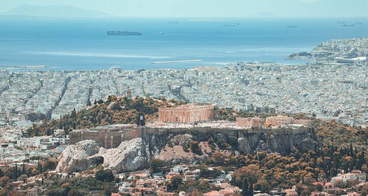 Vue aérienne élevée de l'Acropole avec la mer Égée et les voies de navigation en arrière-plan par une journée brumeuse.