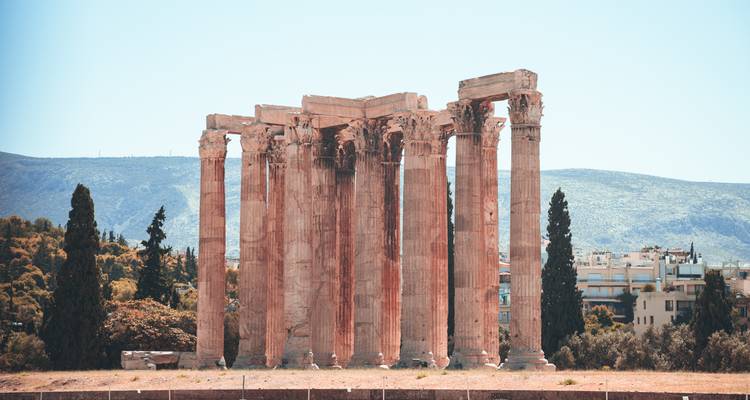 Vestiges du Temple de Zeus Olympien : d'imposantes colonnes corinthiennes se dressent contre un ciel pâle avec des collines au loin.