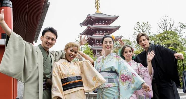 Groupe d'amis portant des kimonos colorés posant joyeusement près d'une pagode dans un temple japonais.