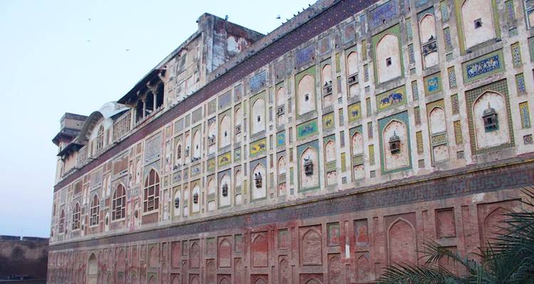 Longue façade décorée du Fort de Lahore montrant des fresques mogholes complexes et des fenêtres cintrées au crépuscule