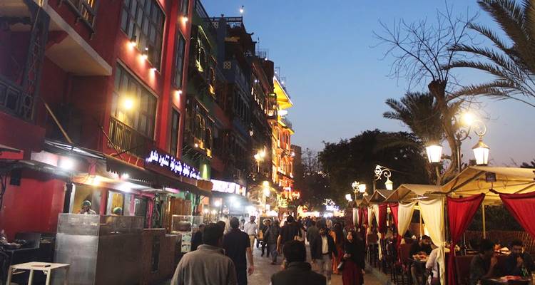 La foule du soir se promène le long d'une rue gastronomique animée avec des lumières vives de restaurants et des terrasses