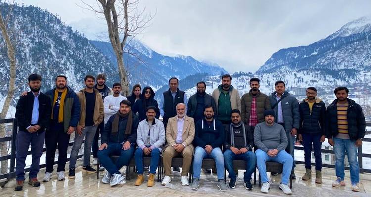 Un groupe d'entreprise pose sur une terrasse surplombant des montagnes enneigées et un village de vallée hivernale