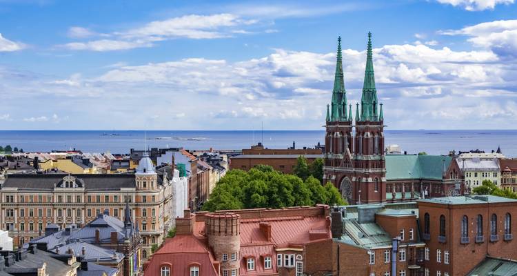Horizon urbain avec église à deux clochers s'élevant au-dessus de la cime des arbres sur fond de mer Baltique