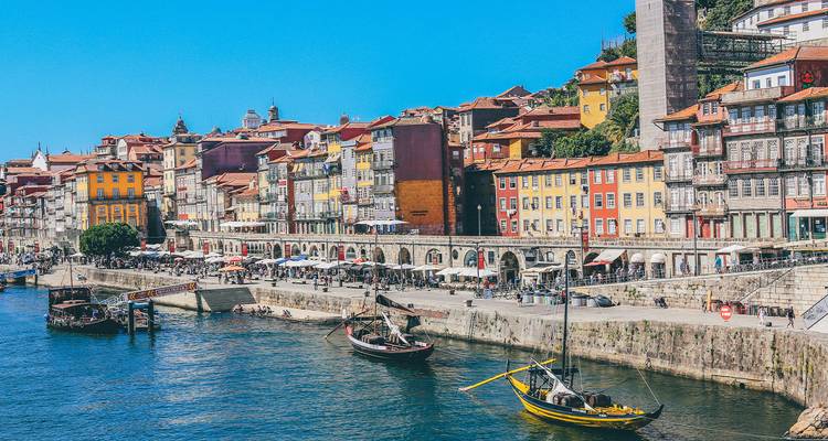 Vibrant Porto waterfront with stacked townhouses, riverside cafes and traditional boats on the Douro.