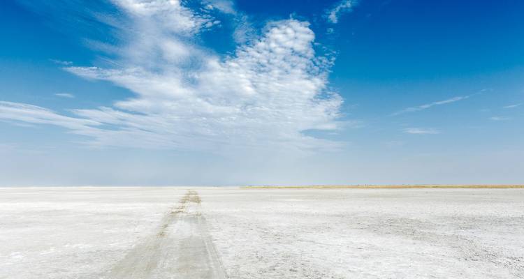 An endless white salt pan stretches to the horizon beneath dramatic blue-and-white skies.