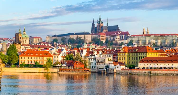 Vue panoramique de l'horizon historique de Prague avec le château et la cathédrale surplombant les maisons aux toits rouges reflétés dans la rivière Vltava.