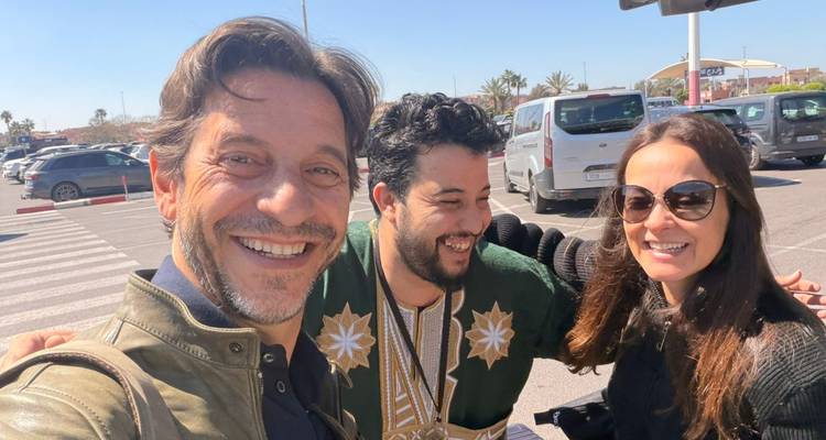 Trio souriant prend un selfie dans un parking ensoleillé au début de leur voyage.