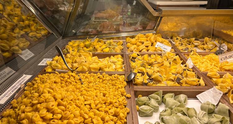 Des plateaux en bois débordant de tortellinis frais et d'autres pâtes faites main sont exposés dans une boutique gastronomique.