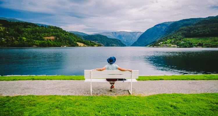 Persoon die ontspant op witte bank met uitzicht op Noors fjord en smaragdgroene bergen