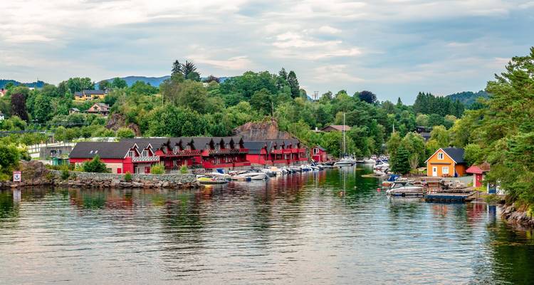 Charmante waterkant met rode botenloodsen, kleurrijke huizen en kleine jachthaven die weerkaatsen in kalm water.