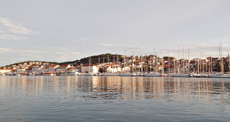 Ville côtière avec des yachts se reflétant sur une eau calme à l'heure dorée.