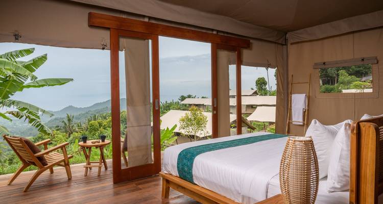 Stijlvolle glamping tent slaapkamer komt uit op een panoramisch uitzicht op de jungle.