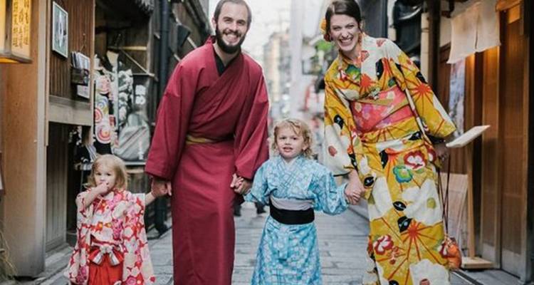 Familie gekleed in kleurrijke kimono's lopend door een smalle traditionele steeg.