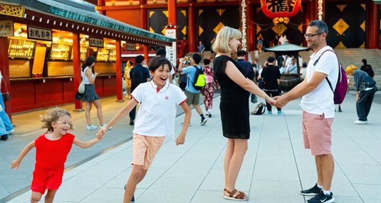Familie die speelt voor de Senso-ji tempel met andere bezoekers op de binnenplaats.
