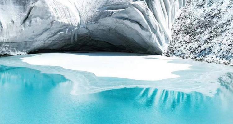 Lac glaciaire turquoise entouré de parois de glace blanche abruptes et de roche couverte de neige.
