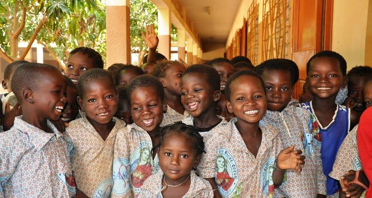 Group of cheerful schoolchildren pose together in a corridor wearing matching uniforms.