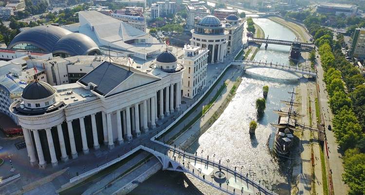 Vue de drone des musées néoclassiques de Skopje, des ponts et de la promenade fluviale par une journée ensoleillée.