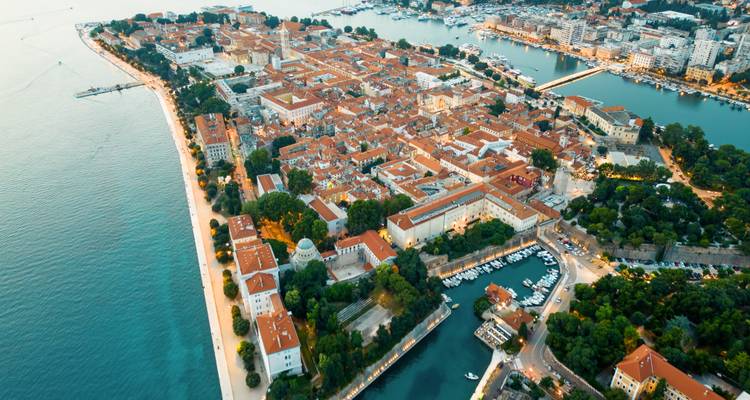 Vista aérea elevada de ciudad costera croata con techos de terracota y mar circundante