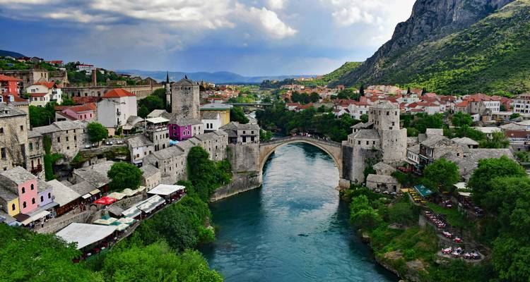 Histórico puente Stari Most que atraviesa el río esmeralda en Mostar rodeado de edificios de piedra