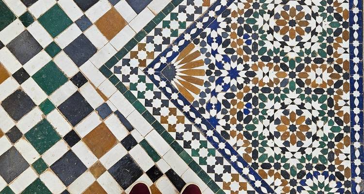Intricate Moroccan mosaic tile floor pattern with feet visible at the bottom edge.