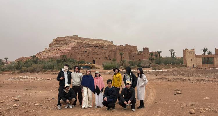 Tour group posing in front of desert kasbah on an overcast day.