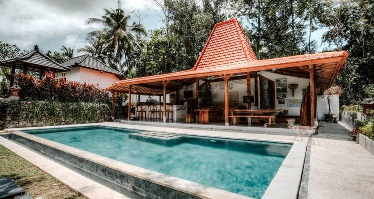 Villa balinesa privada con piscina y techo tradicional estilo joglo entre árboles tropicales