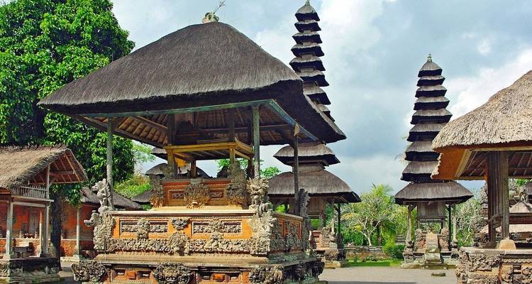 Estructuras ornamentadas de templos balineses with techos de paja de múltiples niveles ubicadas en jardín