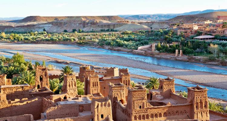 Kasbah fortifié à côté d'une rivière peu profonde avec une vallée fertile et des collines arides au-delà.