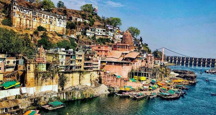 Pittoresk stadje aan de rivier met tempels, kleurrijke huizen en een verre dam onder een heldere blauwe hemel