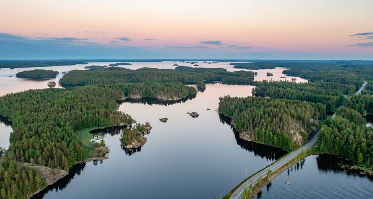 Ruhiges Labyrinth bewaldeter Inseln auf einem stillen See unter einem pastellfarbenen Abendhimmel.