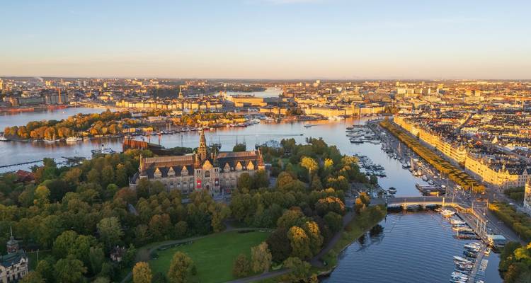 Gouden-uur luchtfoto van Stockholm's eiland Djurgården met musea en waterwegen die glinsteren in warm licht.