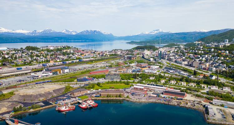 Luchtfoto van Narvik genesteld tussen een fjord en met sneeuw bedekte bergen.